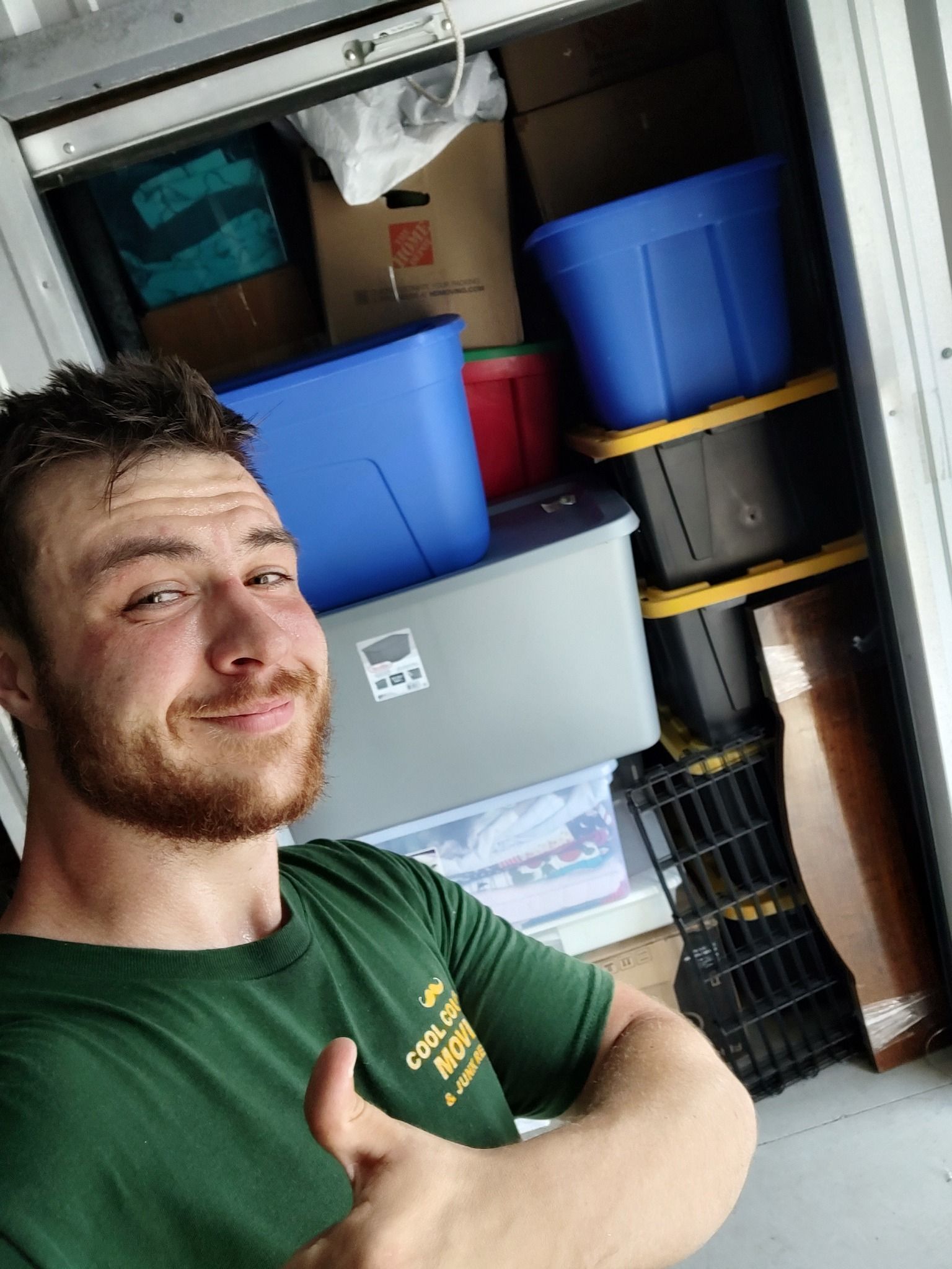 Man taking a selfie in a storage space with stacked plastic bins and shelves in the background