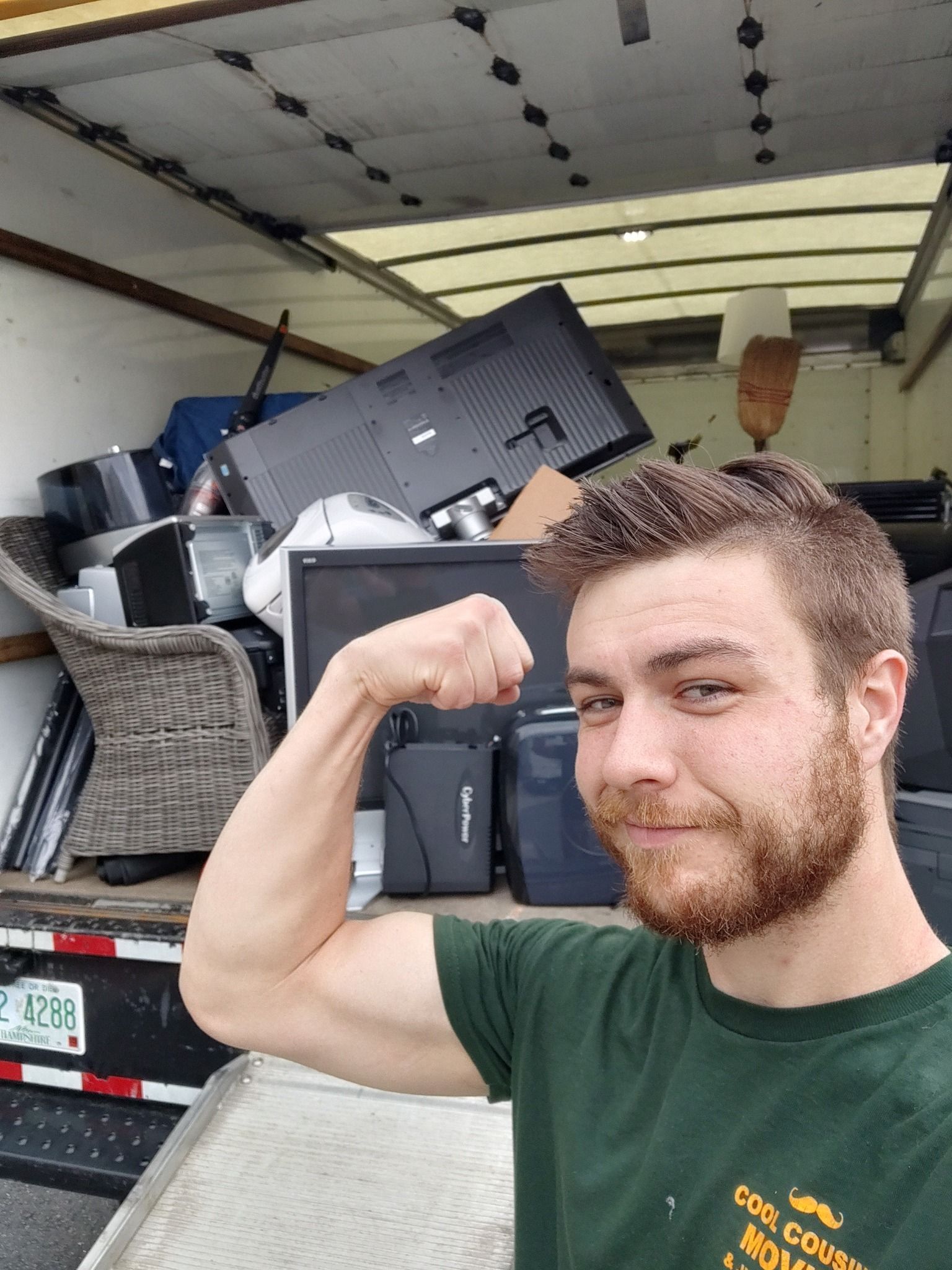 Man flexing in front of a truck packed with moving boxes and furniture