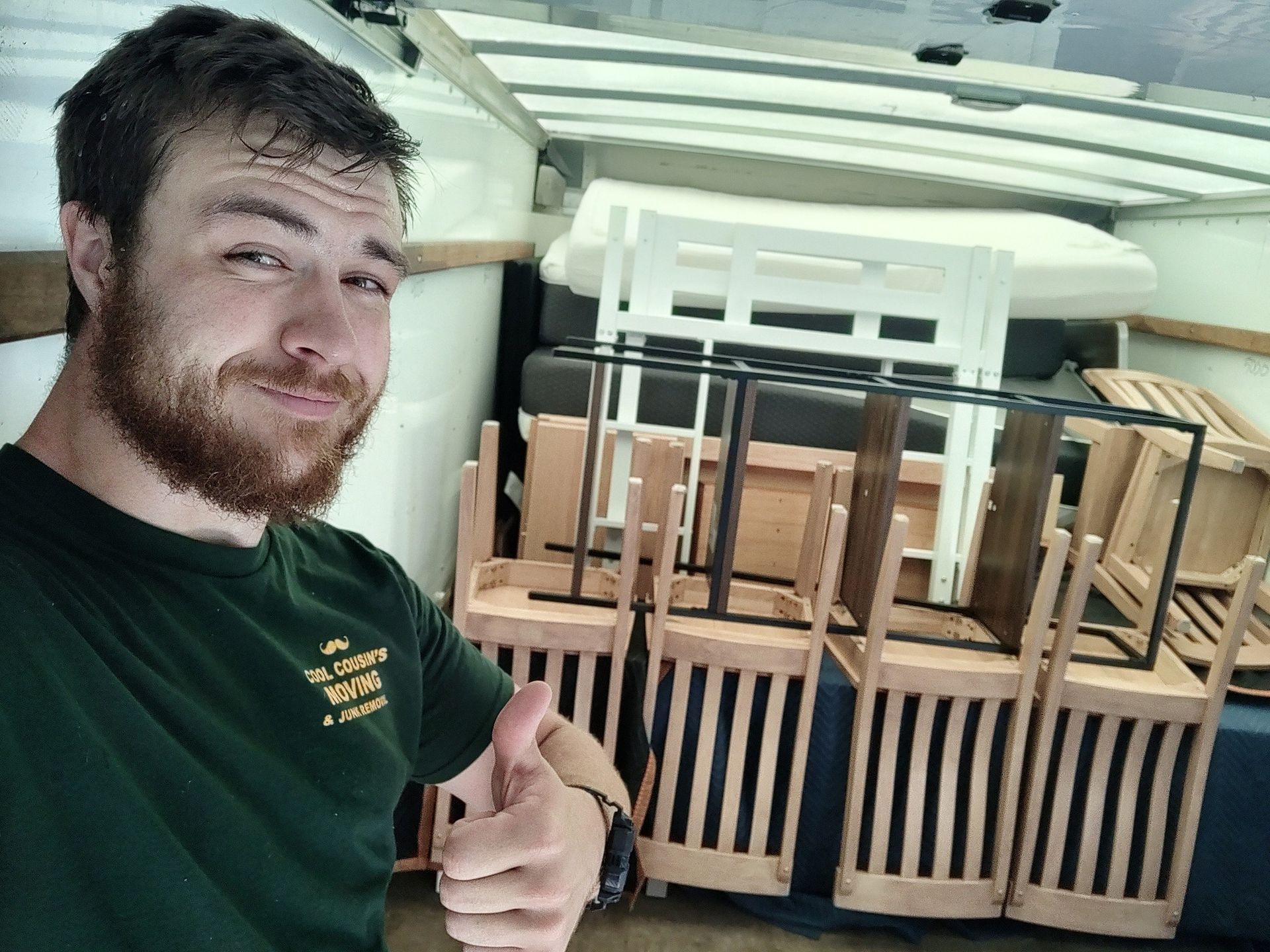 Man giving a thumbs-up beside a wooden crib assembly in a garage or workshop