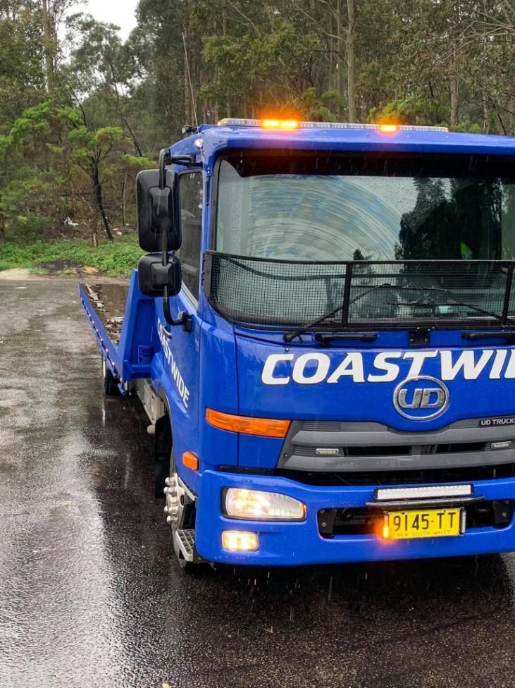 A Blue Tow Truck is Parked on the Side of the Road in the Rain — Coastwide Towing & Transport In Berkeley Vale, NSW