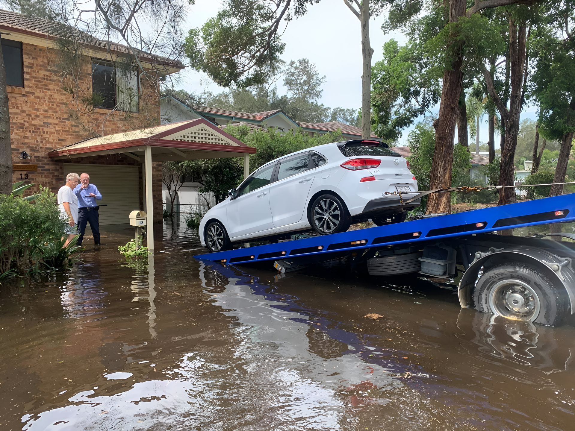 White Car Being Towed From a Flooded Driveway on the New Castle