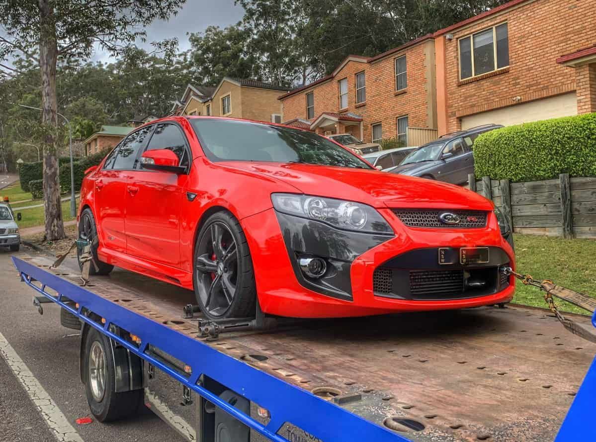A Red Car Is Sitting On Top Of A Tow Truck — Coastwide Towing & Transport In Central Coast, NSW