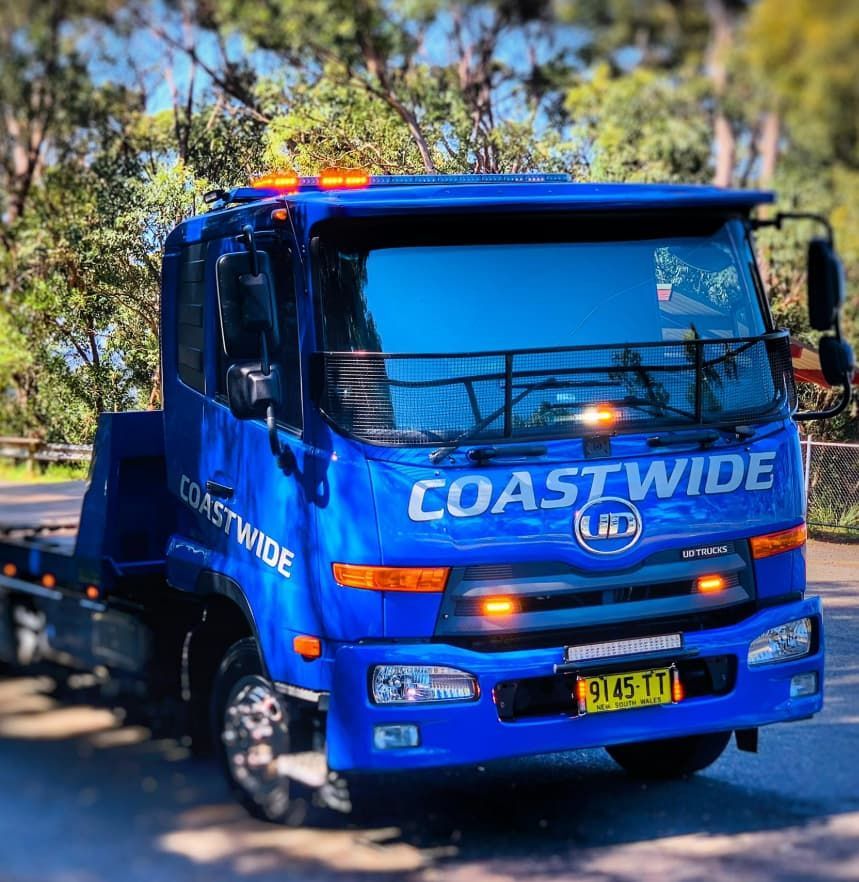 A Blue Coastwide Tow Truck Is Parked On The Side Of The Road — Coastwide Towing & Transport In Maitland, NSW