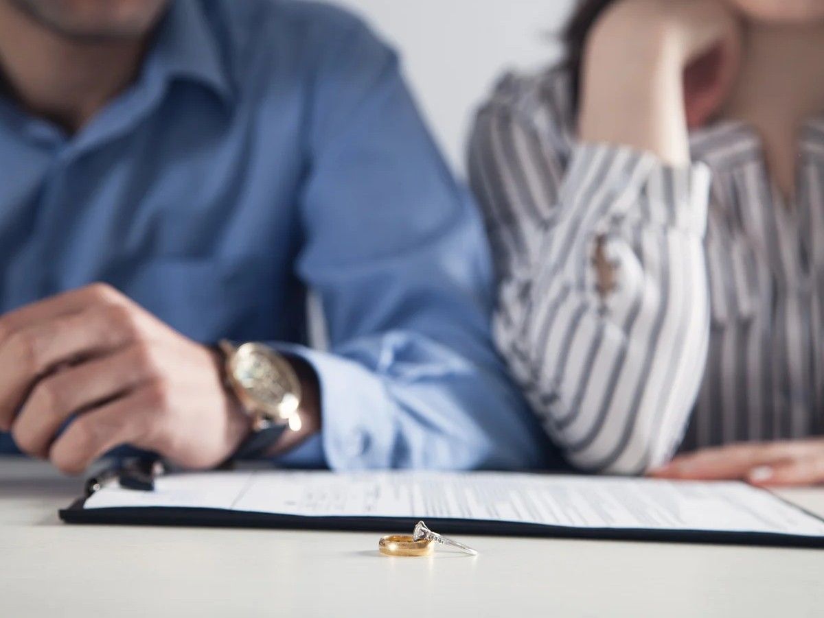 Two people seated at a table reviewing a document, with a ring on the table in front.