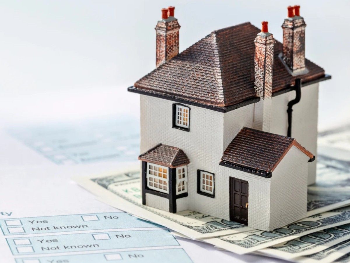 miniture house sitting on money