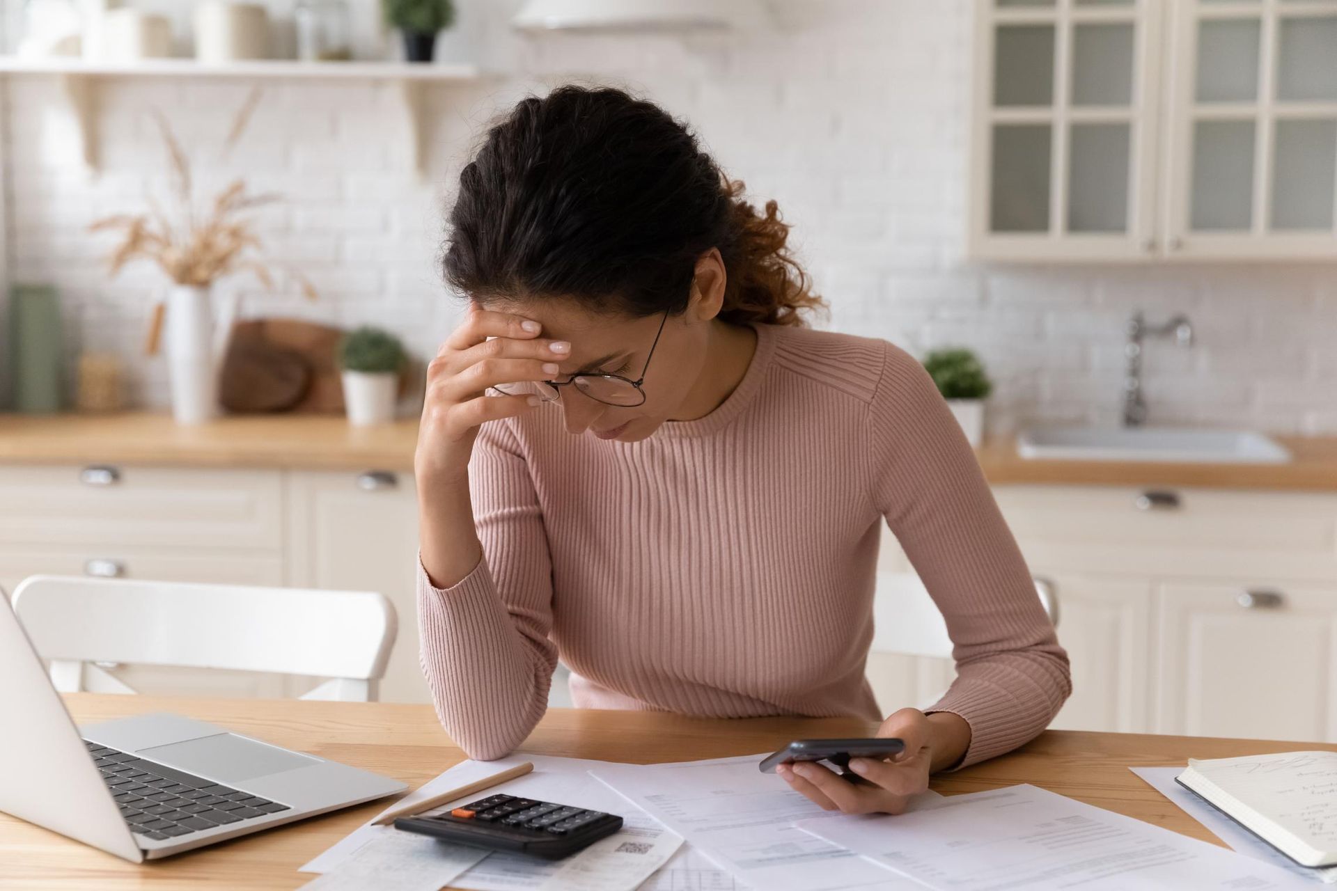 A woman is sitting at a table with a laptop and a calculator.