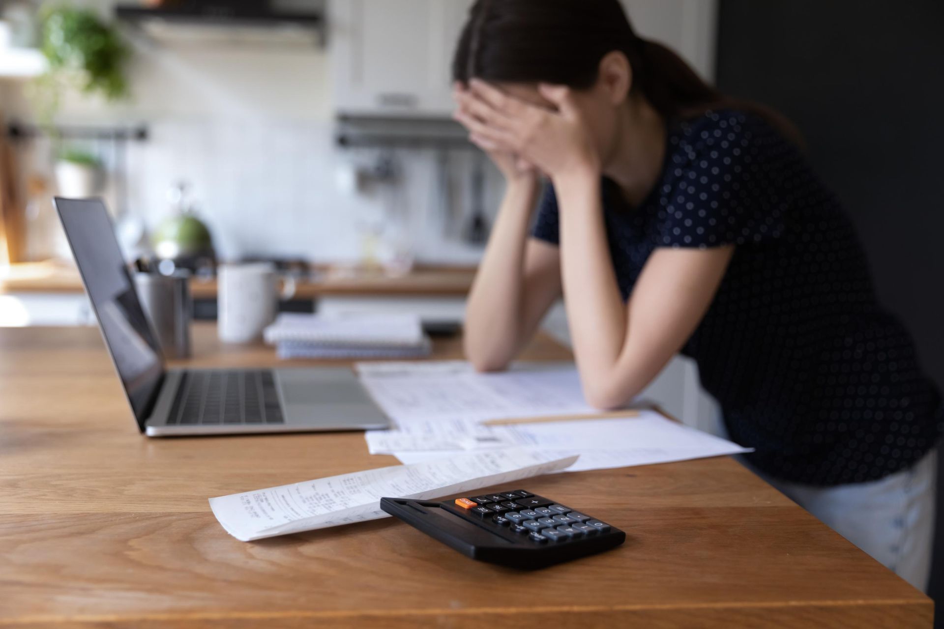 A woman is sitting at a table with a laptop and a calculator.