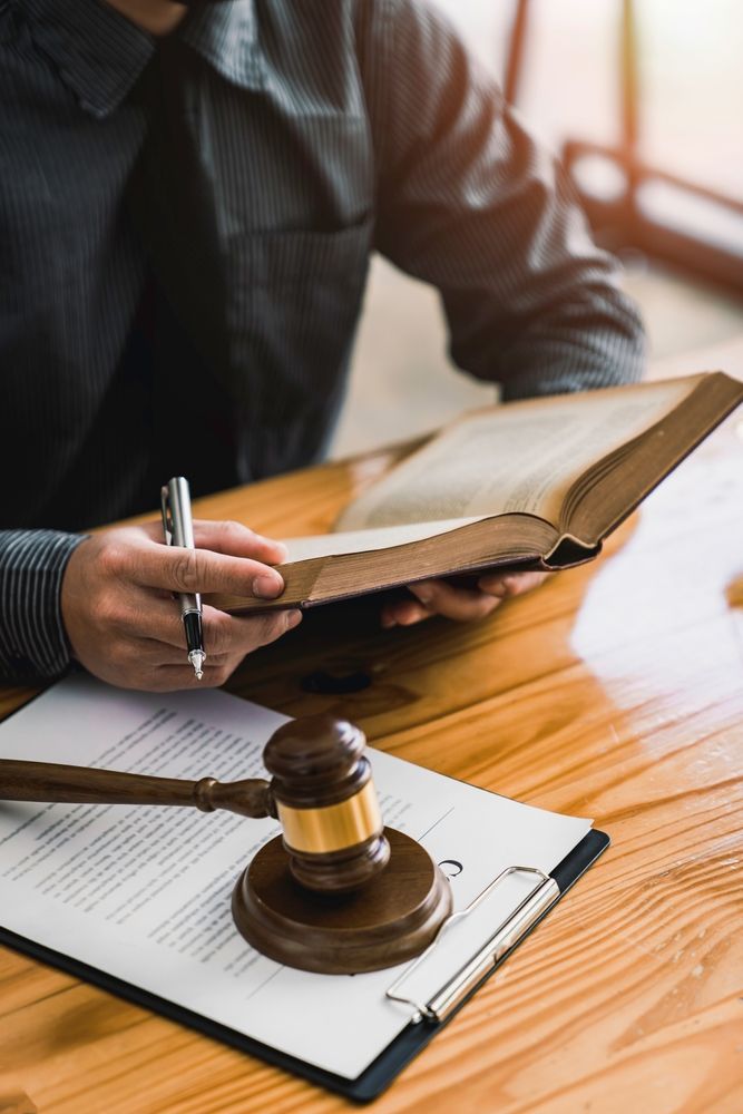 A man is sitting at a table with a clipboard and a judge 's gavel.