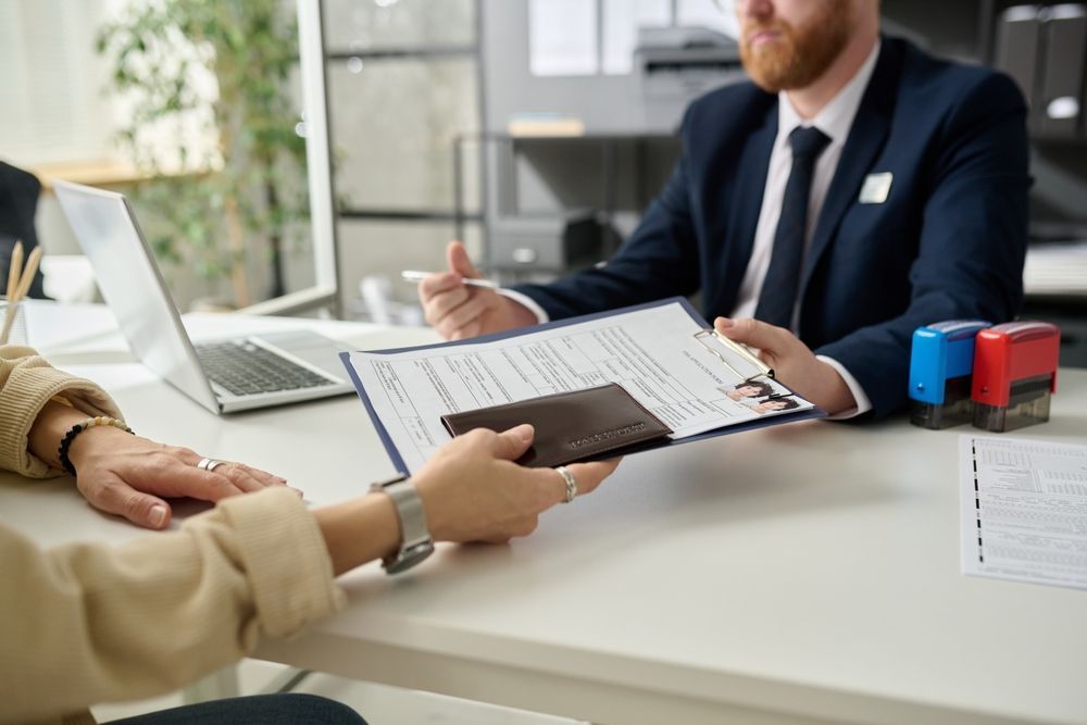 A man in a suit and tie is giving a woman a passport.
