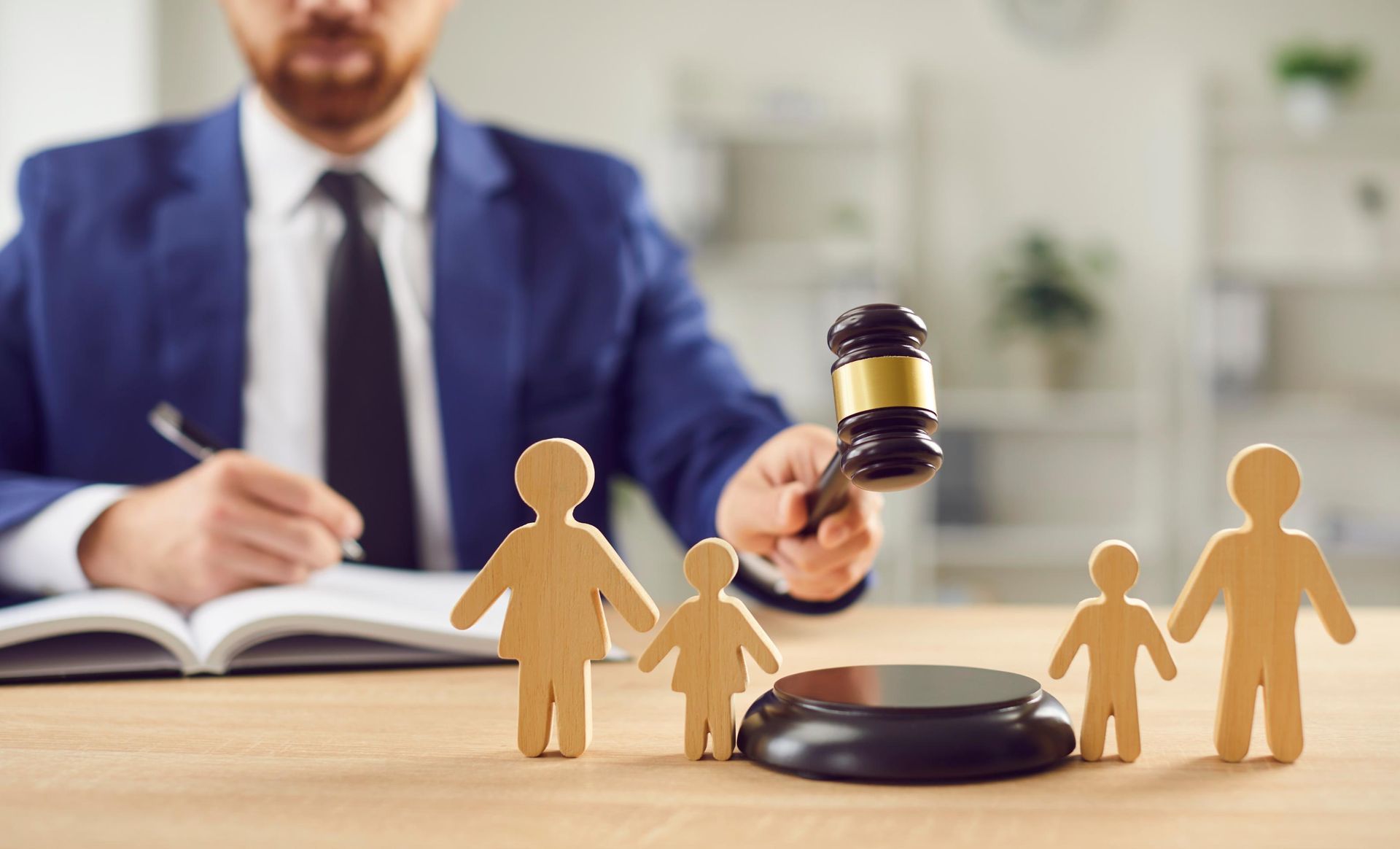 A man is holding a gavel in front of a wooden portrait of a family.