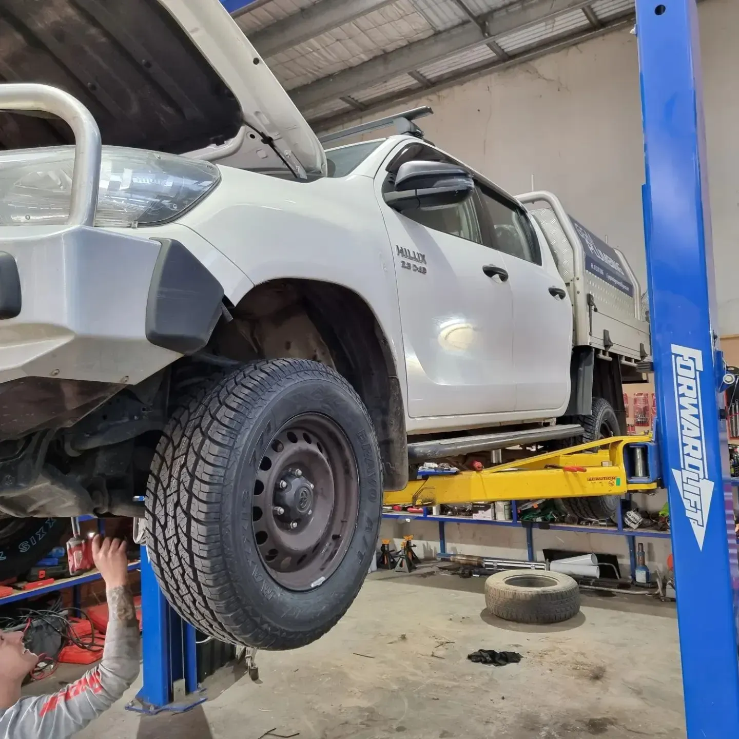 White Pickup Truck Lifted on A Shop Hoist in A Mechanic Garage — Bay City A1 Tyres in North Geelong, VIC