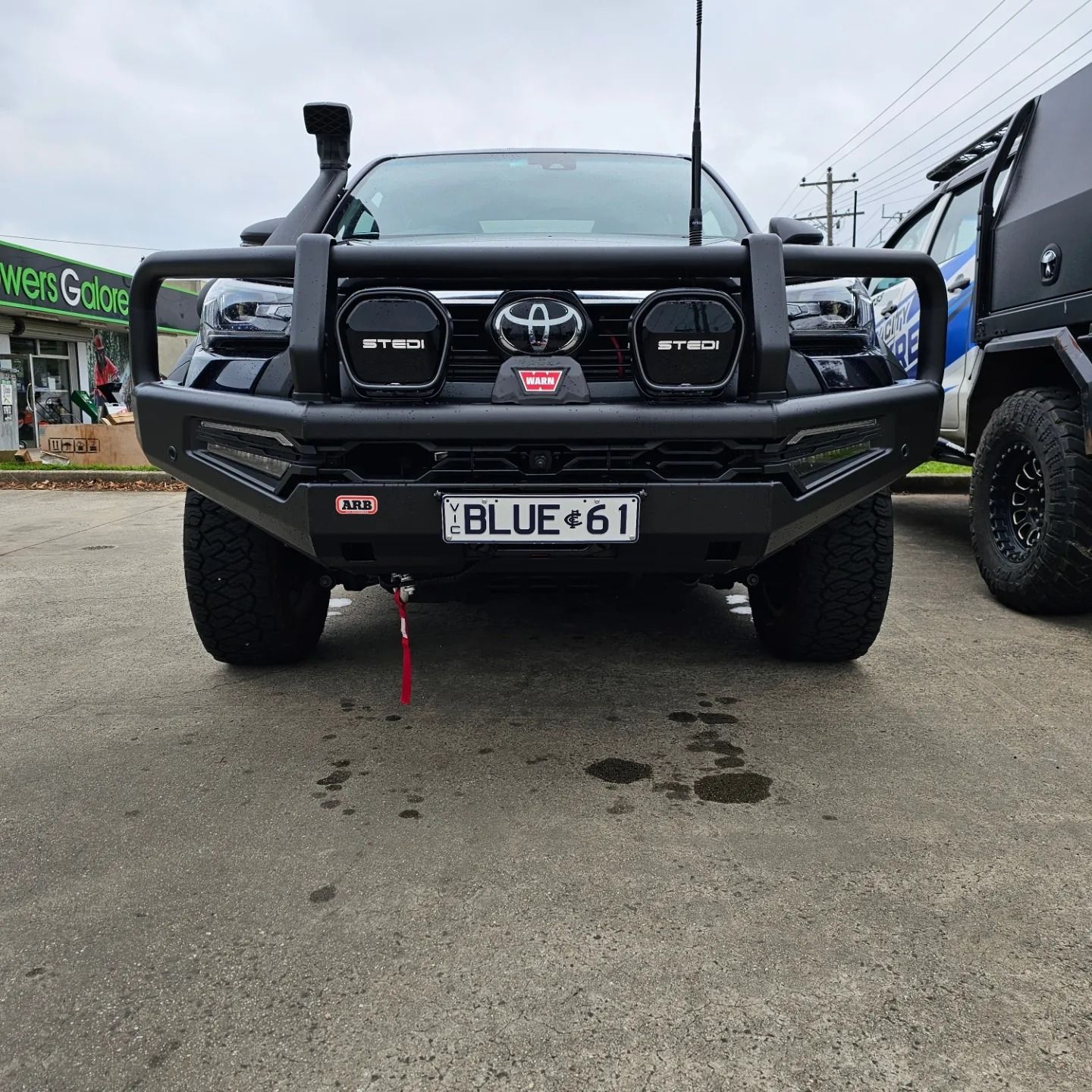 Front view of a black Toyota off-road truck with bull bar and winch, parked on pavement.