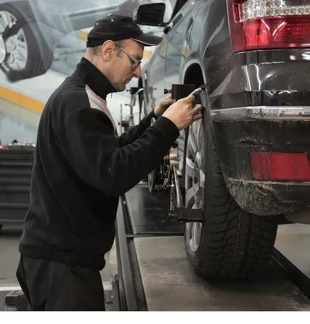 Mechanic Inspecting the Rear Wheel of A Black Suv — Bay City A1 Tyres in North Geelong, VIC