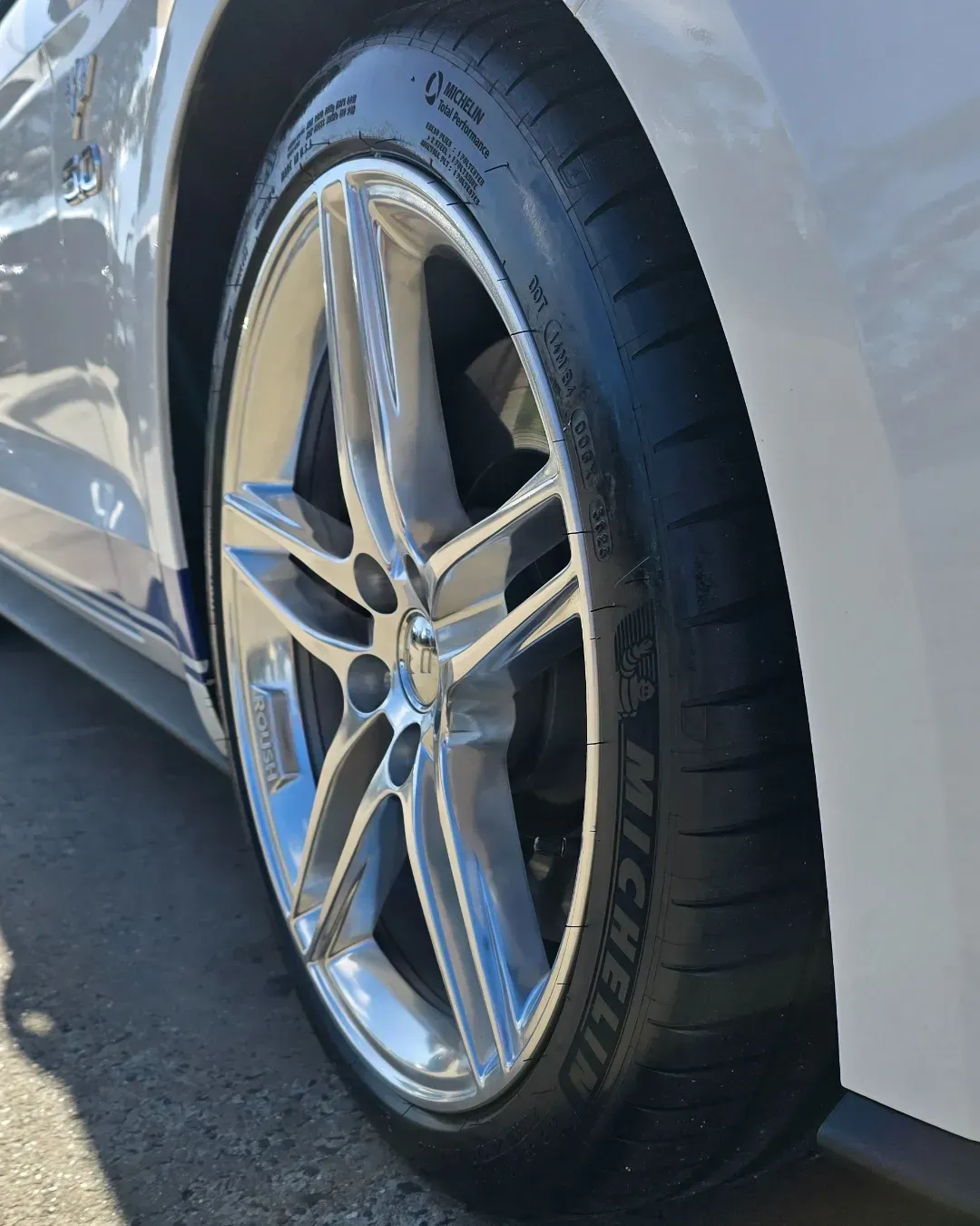 Silver Car Wheel and Tire Beside a White Body Panel on A Road — Bay City A1 Tyres in North Geelong, VIC