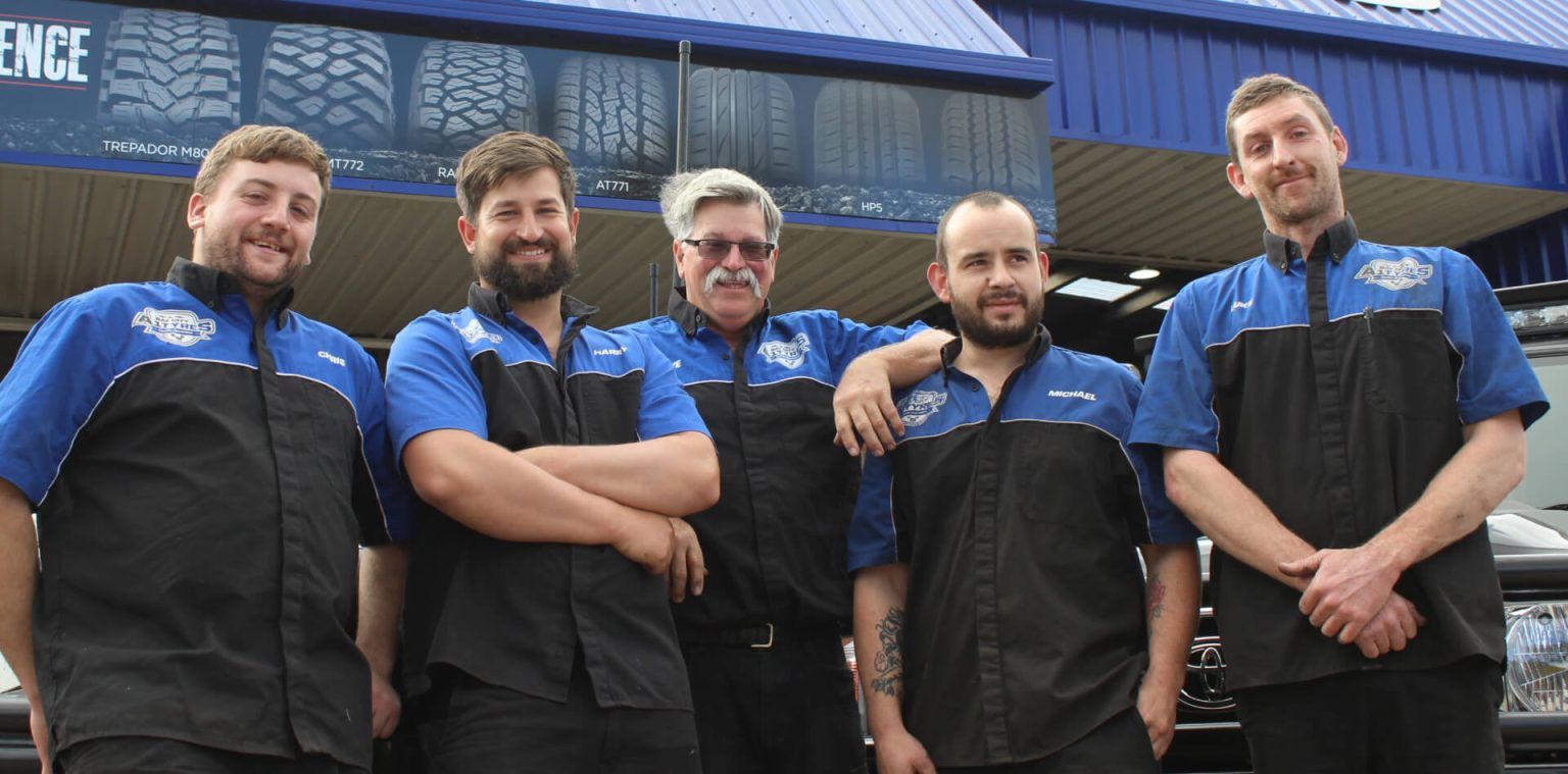 Five Staff in Black Aprons and Blue Shirts Standing Together — Bay City A1 Tyres in North Geelong, VIC