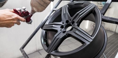 Close Up Of A Person Spray Painting A Black Alloy Car Wheel — Bay City A1 Tyres in North Geelong, VIC