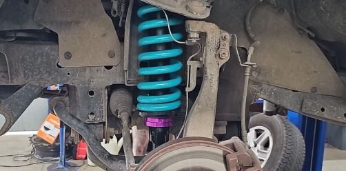 Car Lifted On A Hoist, Showing A Turquoise Coil Spring — Bay City A1 Tyres in North Geelong, VIC