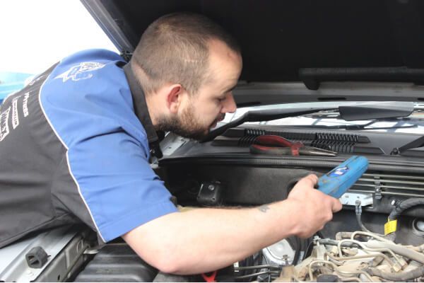 Mechanic Inspecting a Car Engine Under the Hood with A Blue Diagnostic Tool — Bay City A1 Tyres in North Geelong, VIC