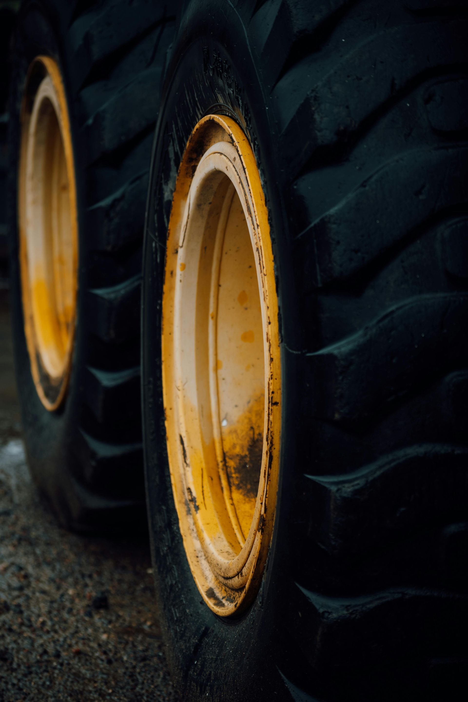 Close-Up of Large Yellow-Rimmed Tractor Wheels on A Dark Gravel Surface — Bay City A1 Tyres in North Geelong, VIC