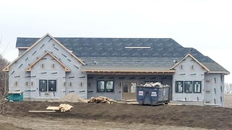 A large house under construction with a dumpster in front of it.