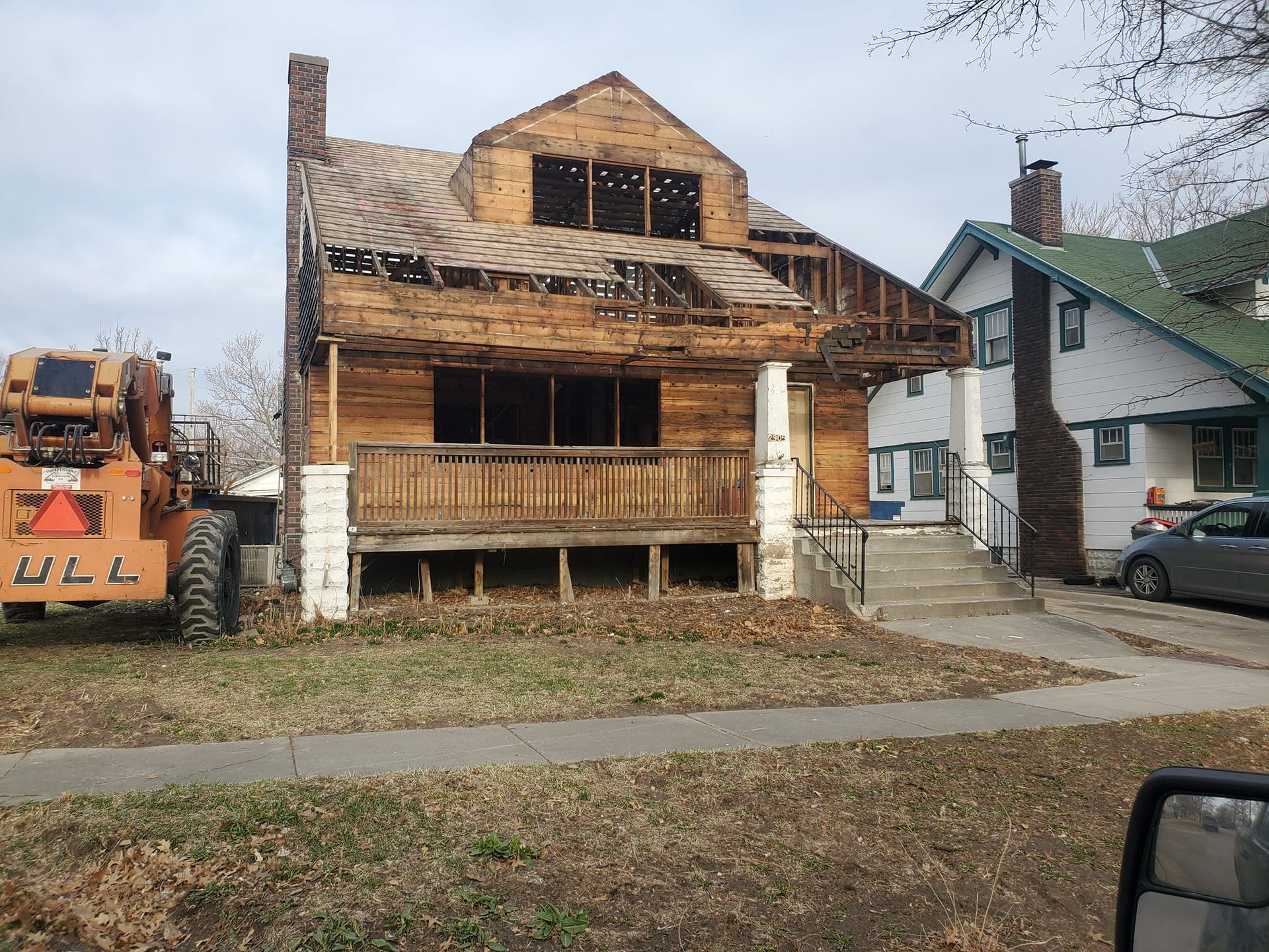 A tractor is parked in front of a house that is being demolished.