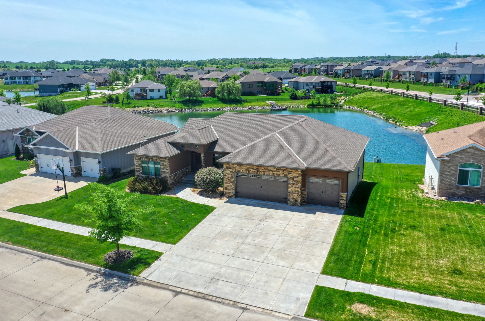 An aerial view of a house in a residential area with a lake in the background.