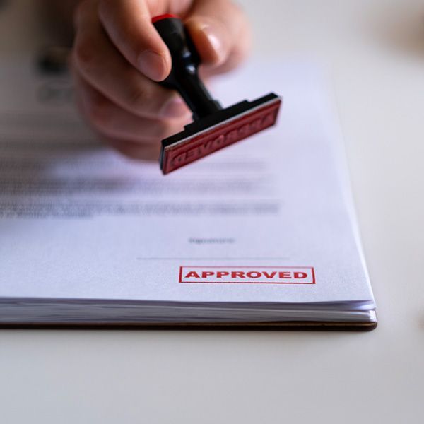 Hand stamping “APPROVED” on a document