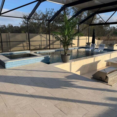 Screened patio with pool, hot tub, lounge chairs, and potted palm in sunlight