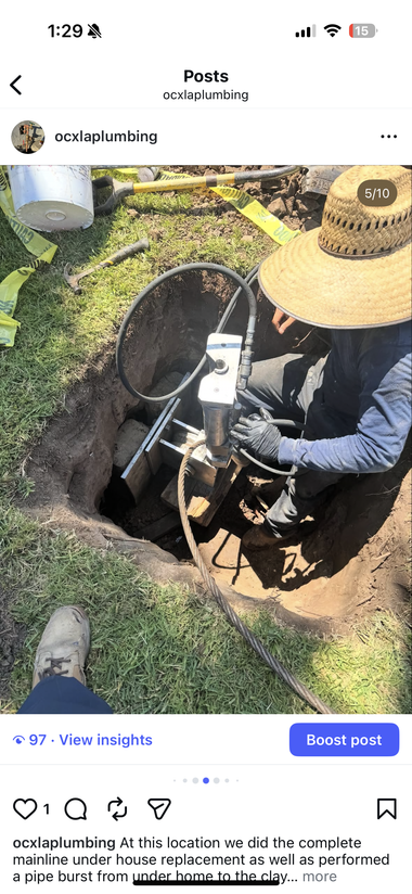 Exposed underground pipe joint in a dirt trench with a red cable beside it
