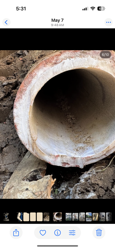 Copper pipes with a black water meter and green hose against a wall near the floor.