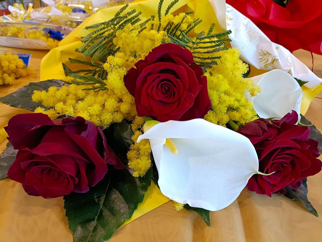 Bouquet di rose rosse, calle bianche e fiori gialli avvolto in carta gialla