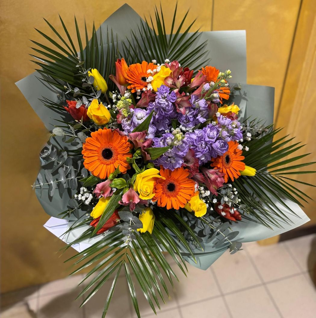 Bouquet di rose rosse con foglie verdi, composto fitto in un ambiente luminoso