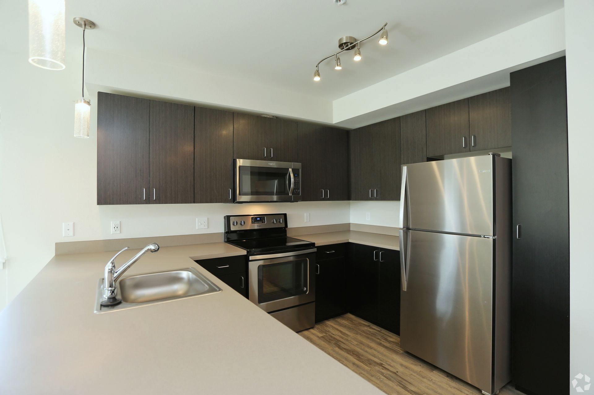 Modern kitchen with gray cabinets, stainless steel appliances, and light countertops.