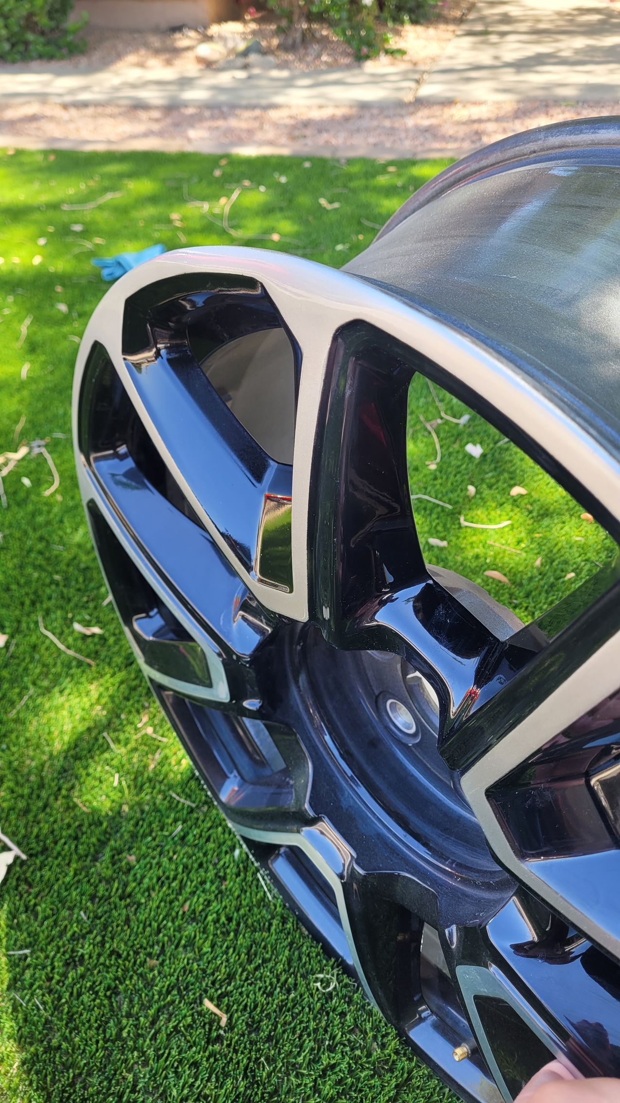 A close up of a car wheel sitting on top of a lush green field.