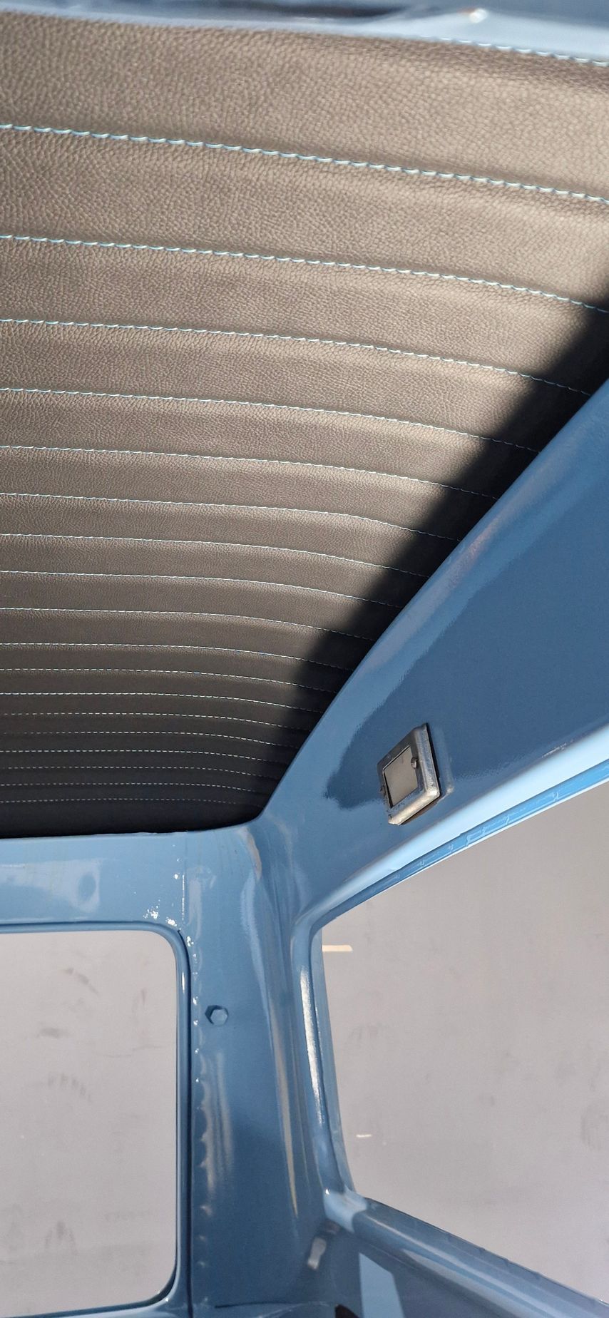 Interior view of a vehicle showing a textured grey headliner and light blue metal roof framing with a small cabin light — Tidy Trim Newcastle in Carrington, NSW