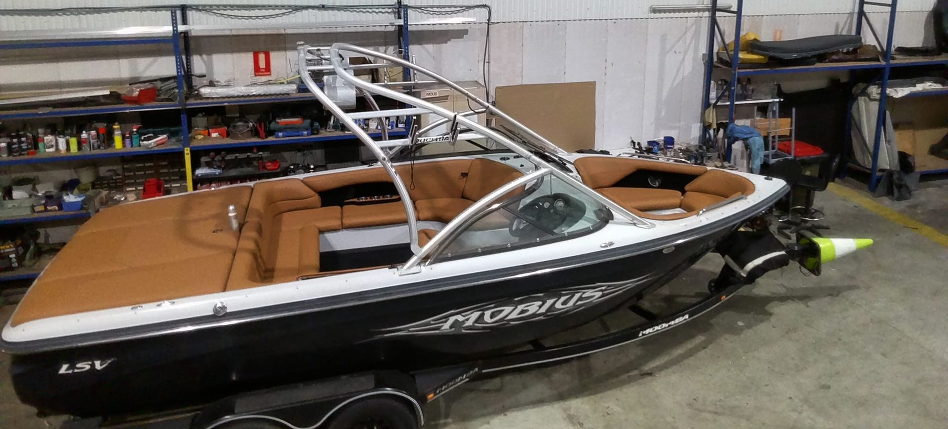 A black and white ski boat with tan upholstery parked inside a garage on a trailer — Tidy Trim Newcastle in Carrington, NSW