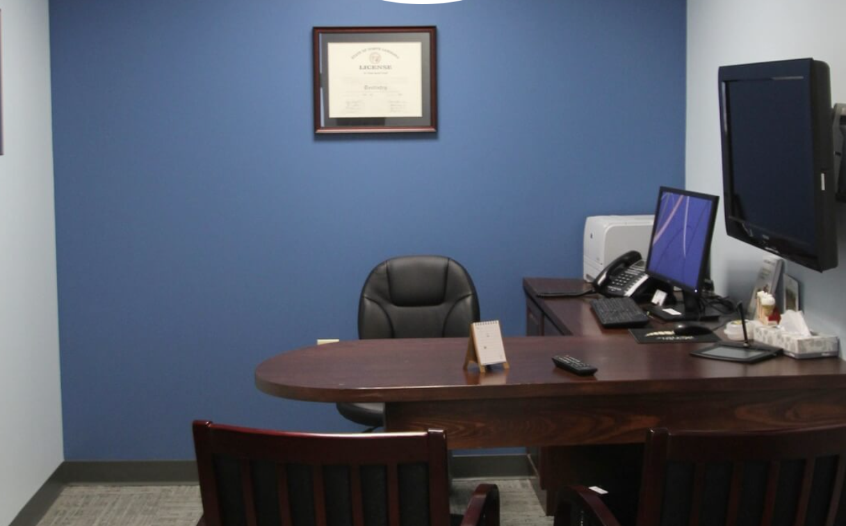 A small office with a blue wall and a desk with a computer on it