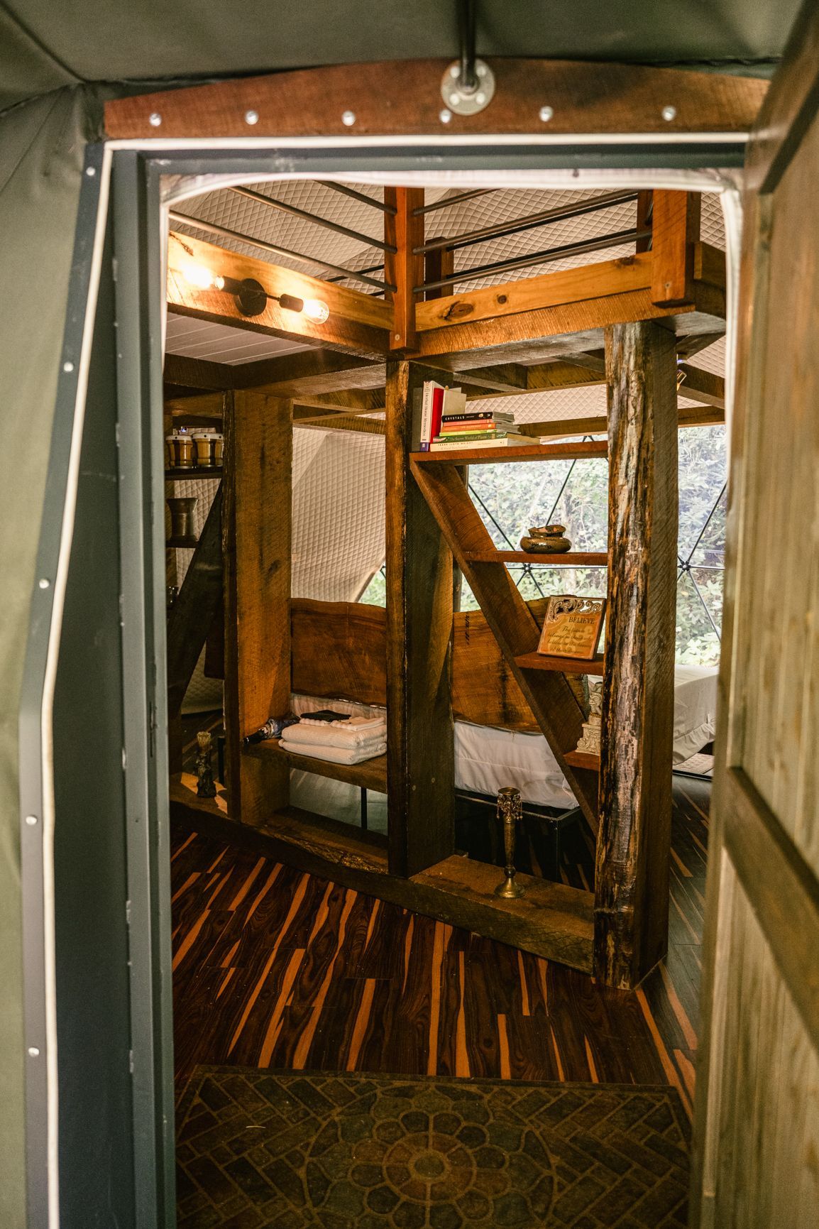 View of the interior of a small, wooden cabin with a loft area, through a doorway.