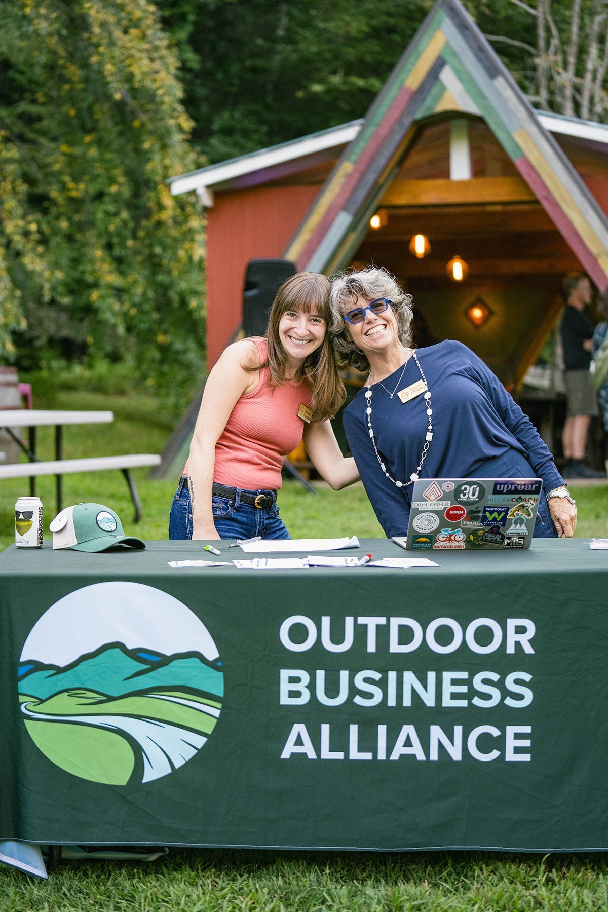Two people stand behind a table for an event.