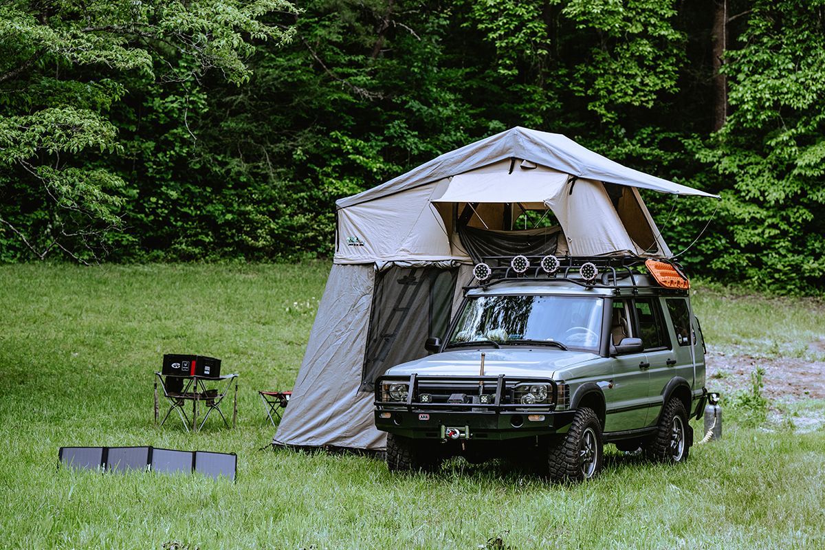 An overlanding SUV sits in a grassy field.
