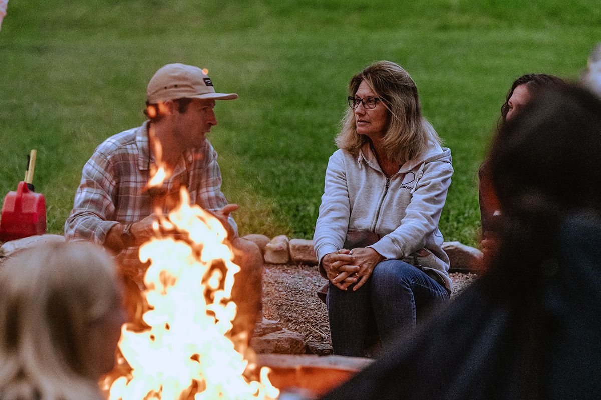 A man and woman sit next to a fire pit.