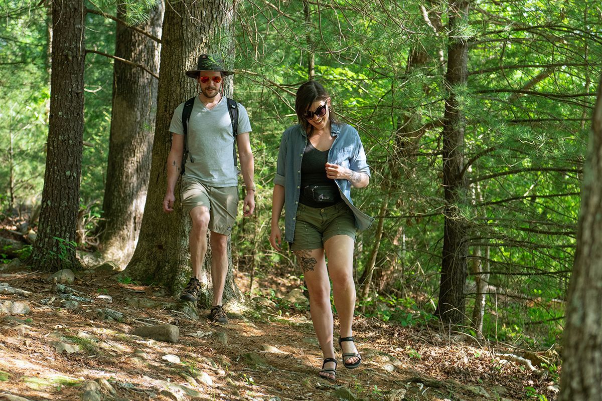 A man and a woman are walking down a path in the woods.