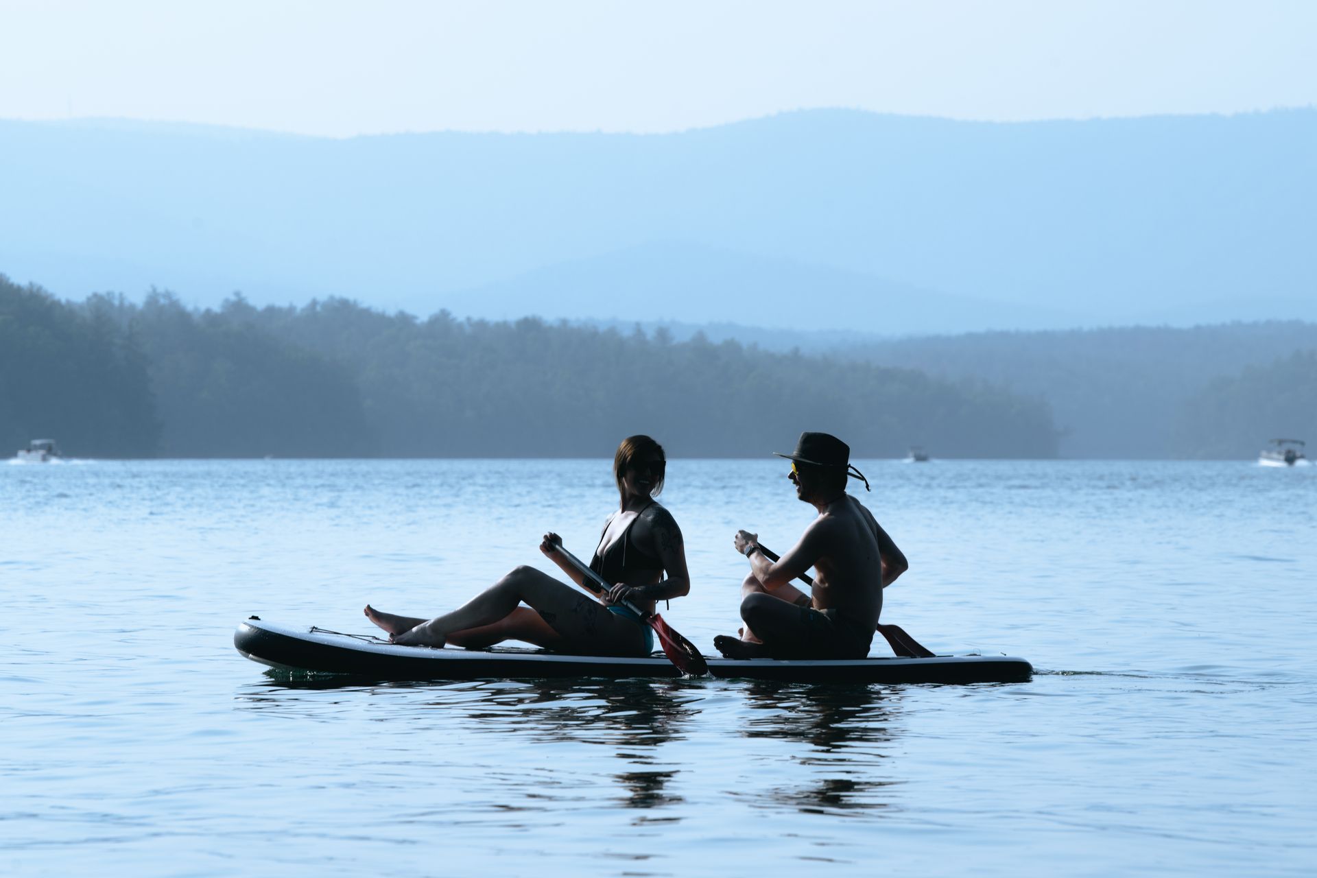 Two people are sitting on a paddle board in the water.