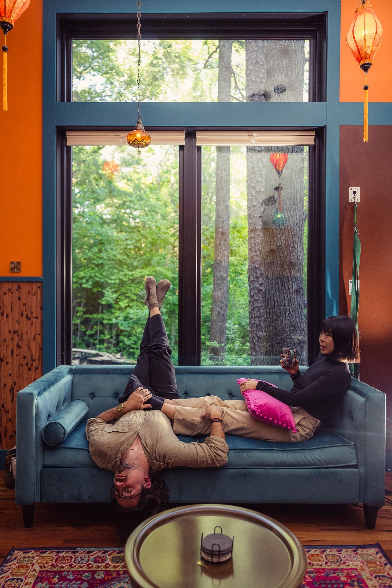 Two people reading books in warm sunlight in a recessed lounge area of a cabin.