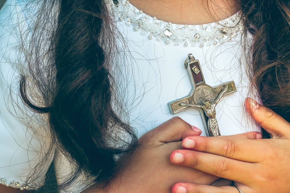 A little girl is holding a cross in her hands.