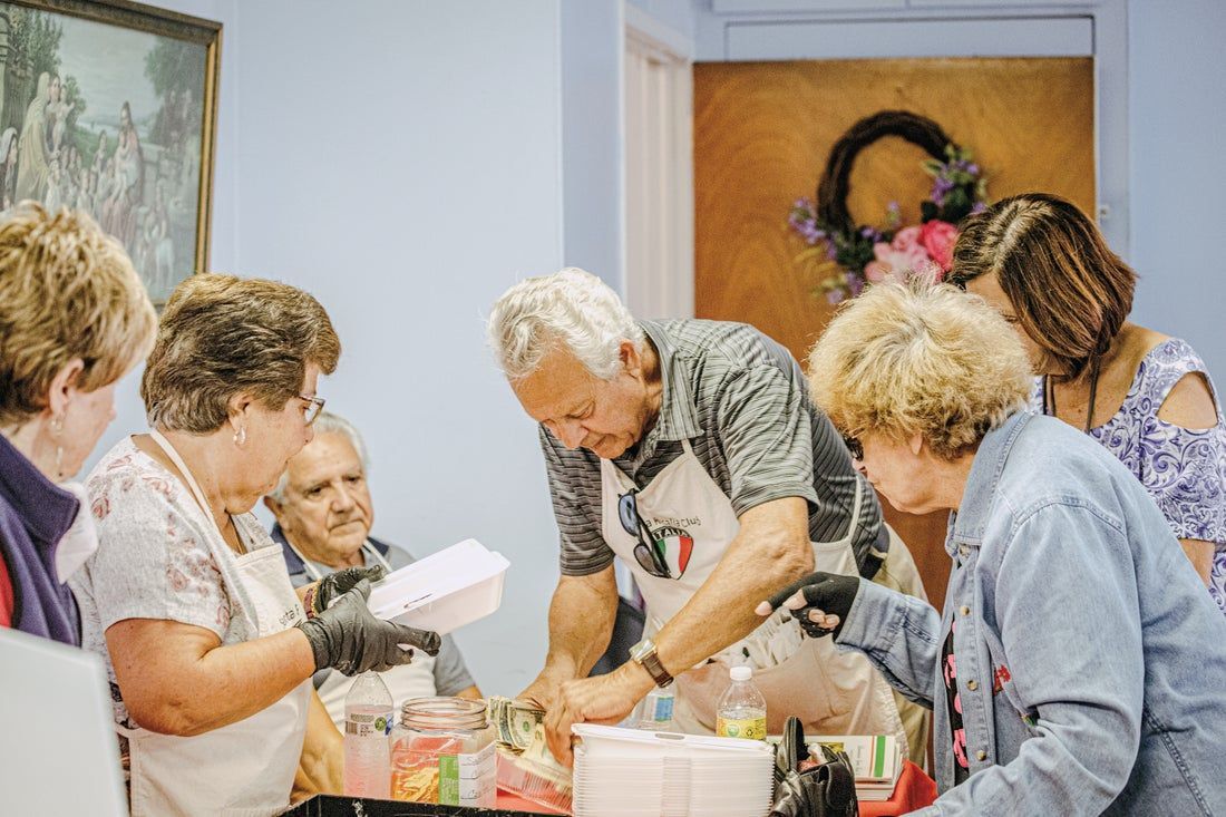 A group of people are standing around a table preparing food.