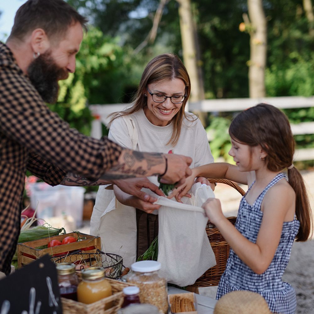 A family reaching into a plastic bag pulling out picnic food