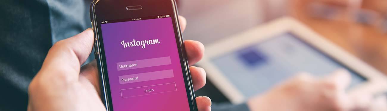 A person is holding a cell phone showing the Instagram login page in their hand.