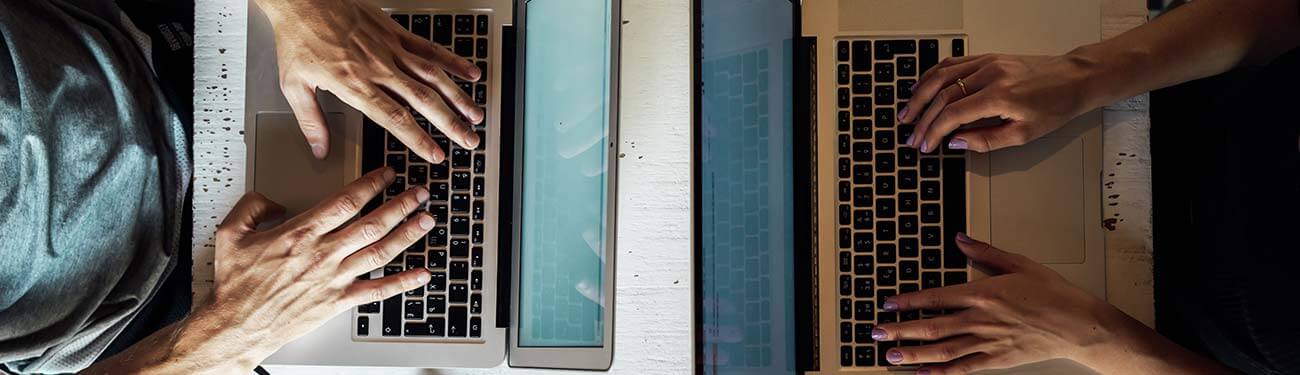 A group of people are typing on laptops at a table.