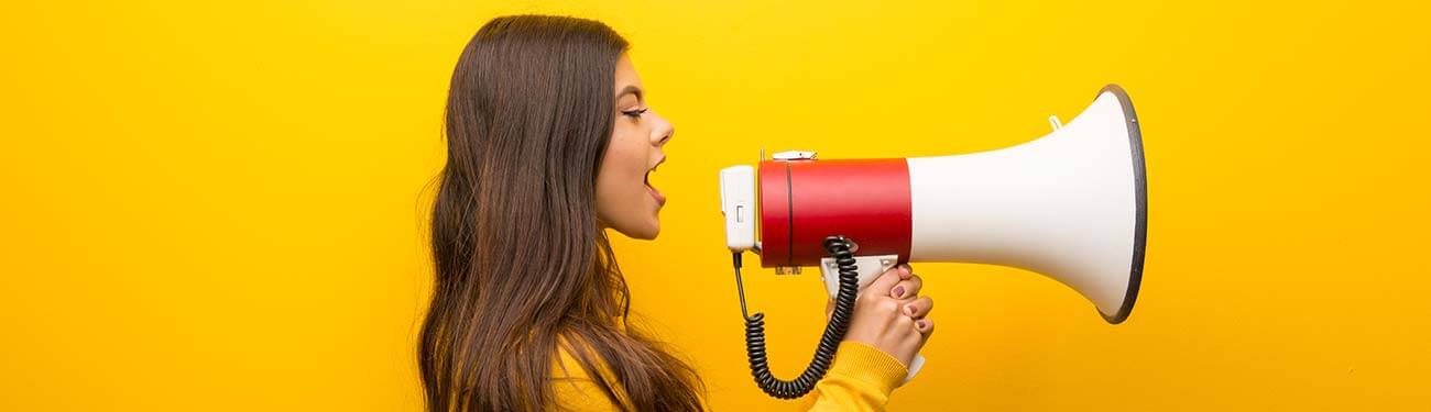 A woman is screaming into a megaphone on a yellow background.